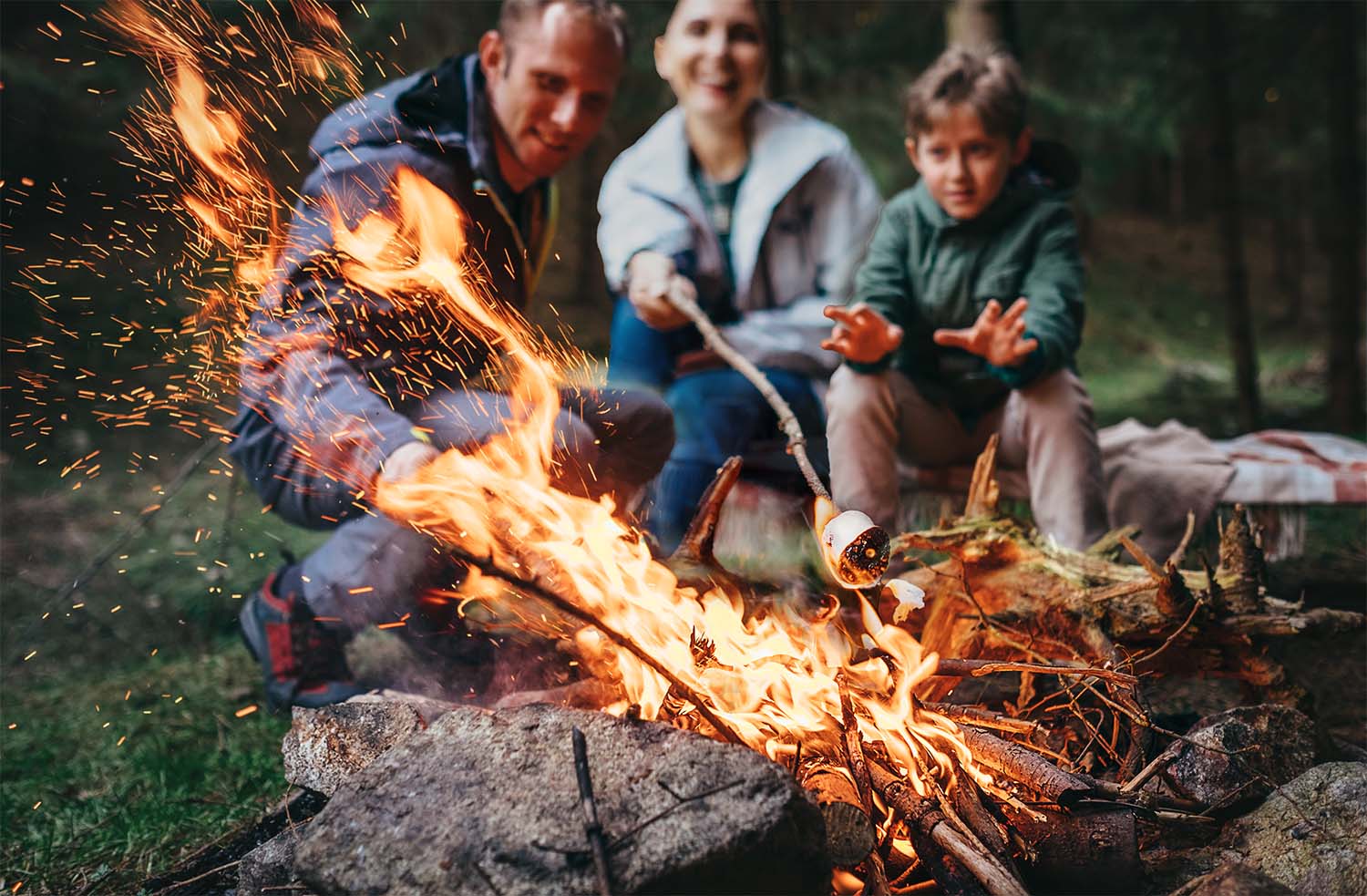 Mid 40s couple with kids enjoying a campfire.